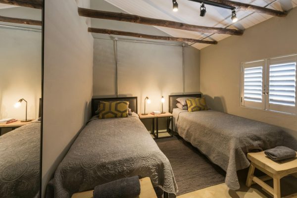 a neat room with two single beds and an open truss ceiling