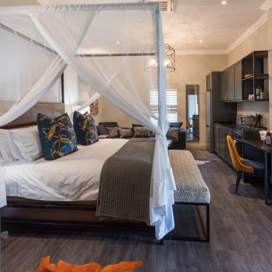 a beautifully decorated room with an african theme, large 4-poster king size bed draped mosquito netting
