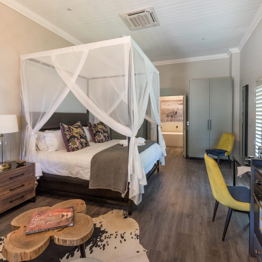 a beautifully decorated room with an african theme, large 4-poster king size bed draped mosquito netting