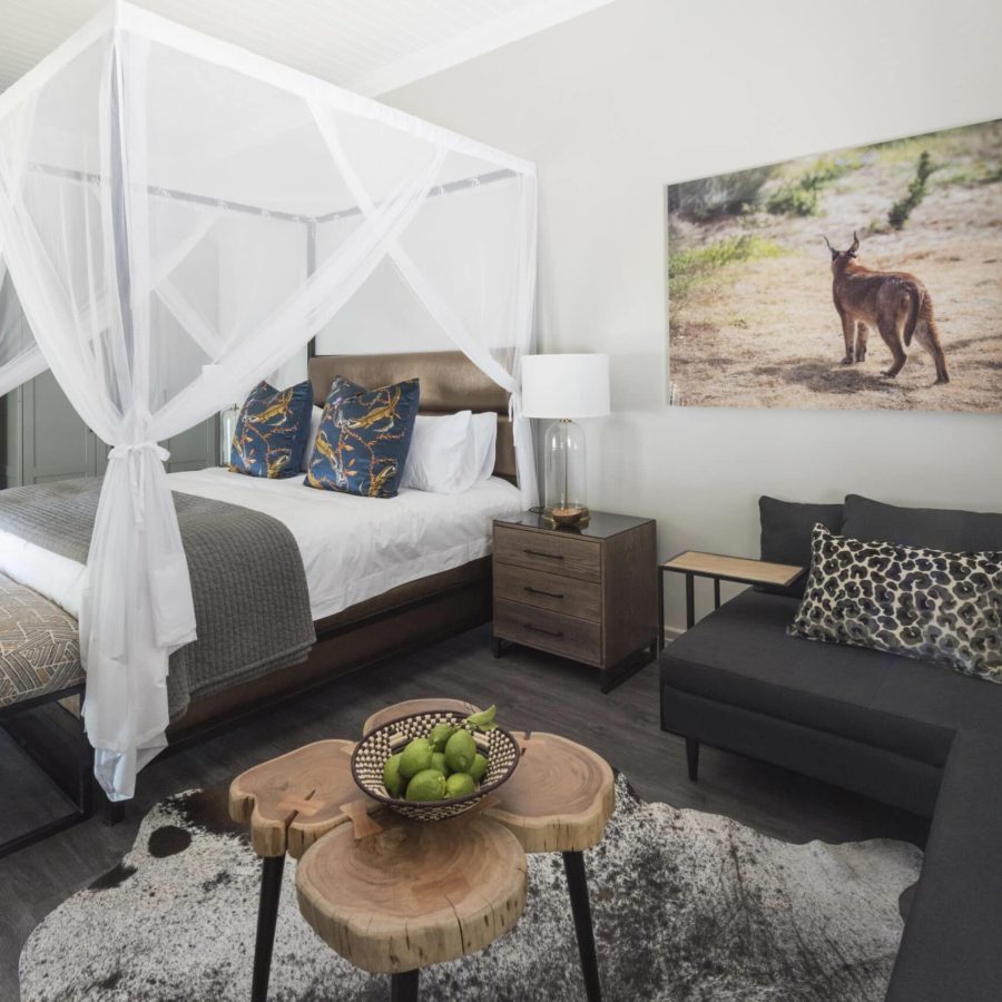 a beautifully decorated room with an african theme, large 4-poster king size bed draped mosquito netting, lounge area and desk