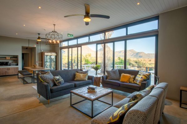 an african themed plush lounge lounge and dining area looking out onto a patio with mountains in the distance
